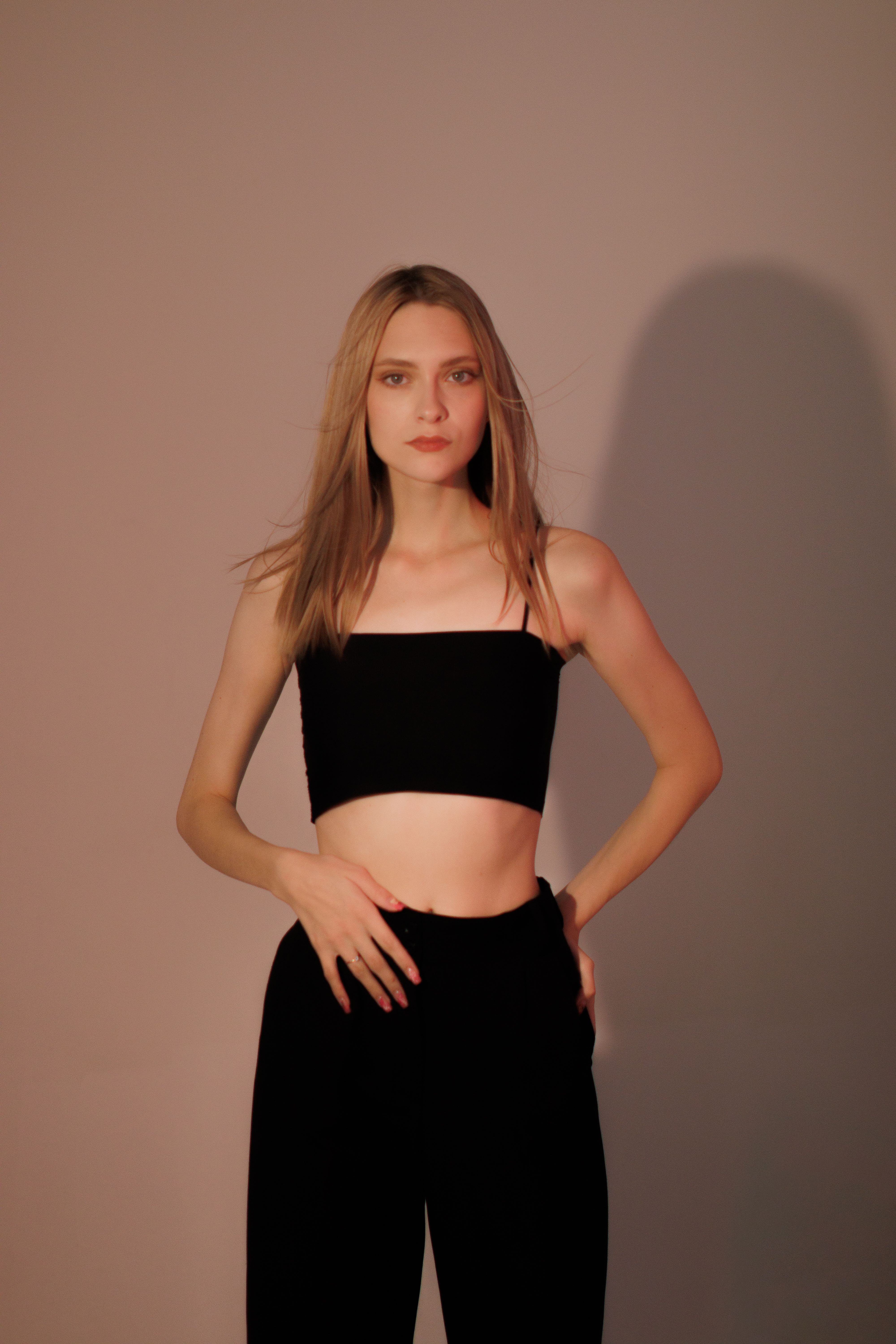 Stylish portrait of a blonde woman in a black outfit posing in a studio setting.
