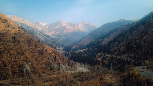 Free Captivating aerial view of a picturesque mountain valley with trees and hills under a clear sky. Stock Photo