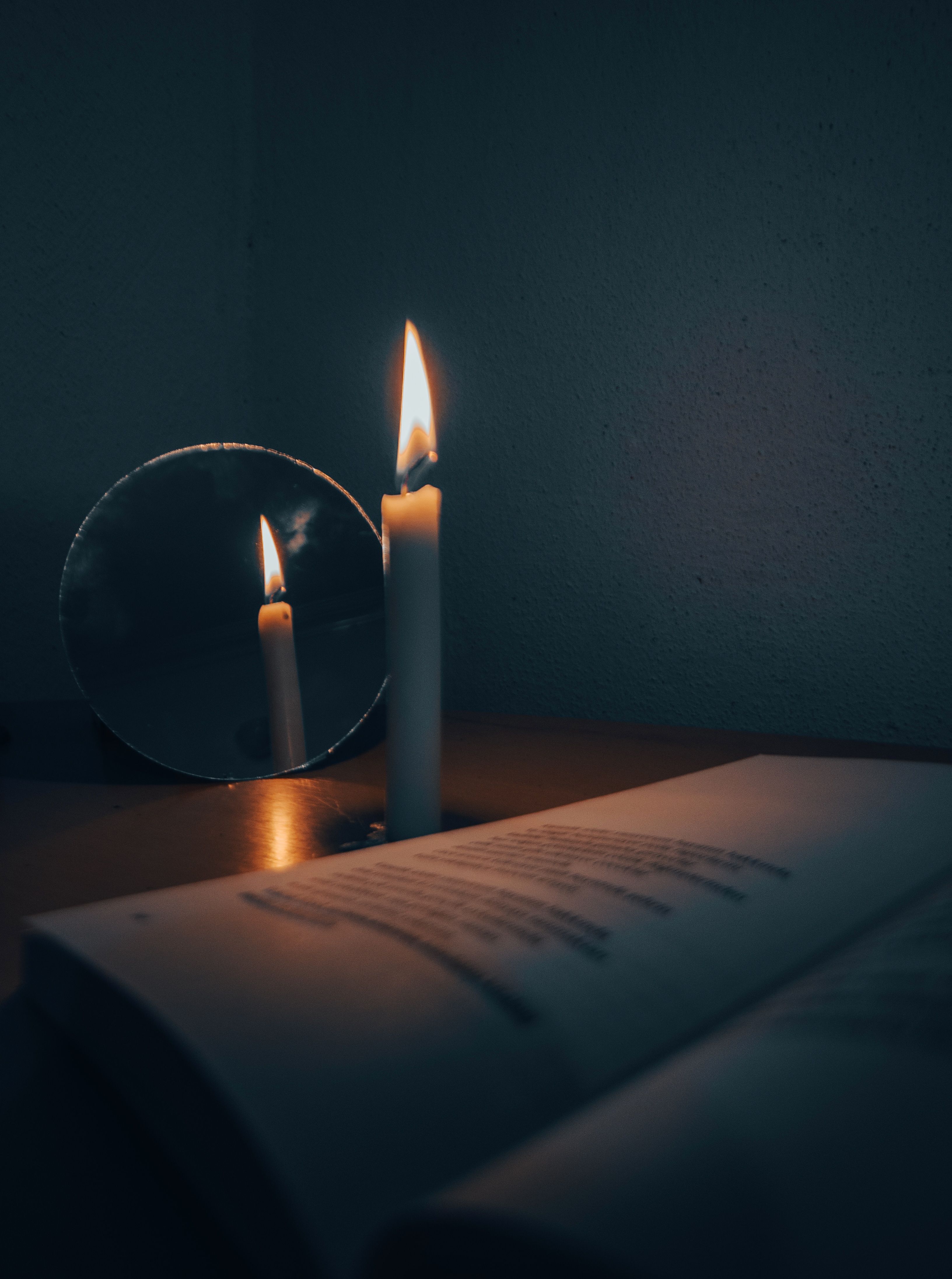 A candle burning beside an open book in a calm, quiet setting