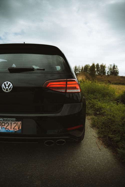 Free A black Volkswagen car parked on a rural road, evoking a travel and adventure theme. Stock Photo