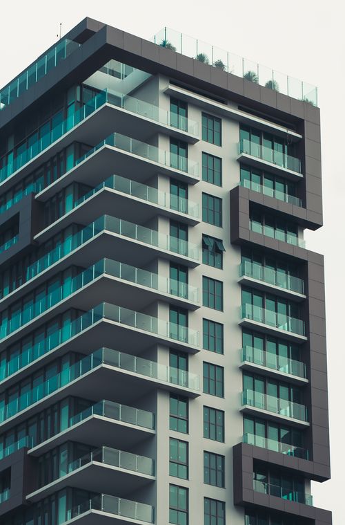 Free A sleek modern high-rise with turquoise glass facade and balconies. Stock Photo