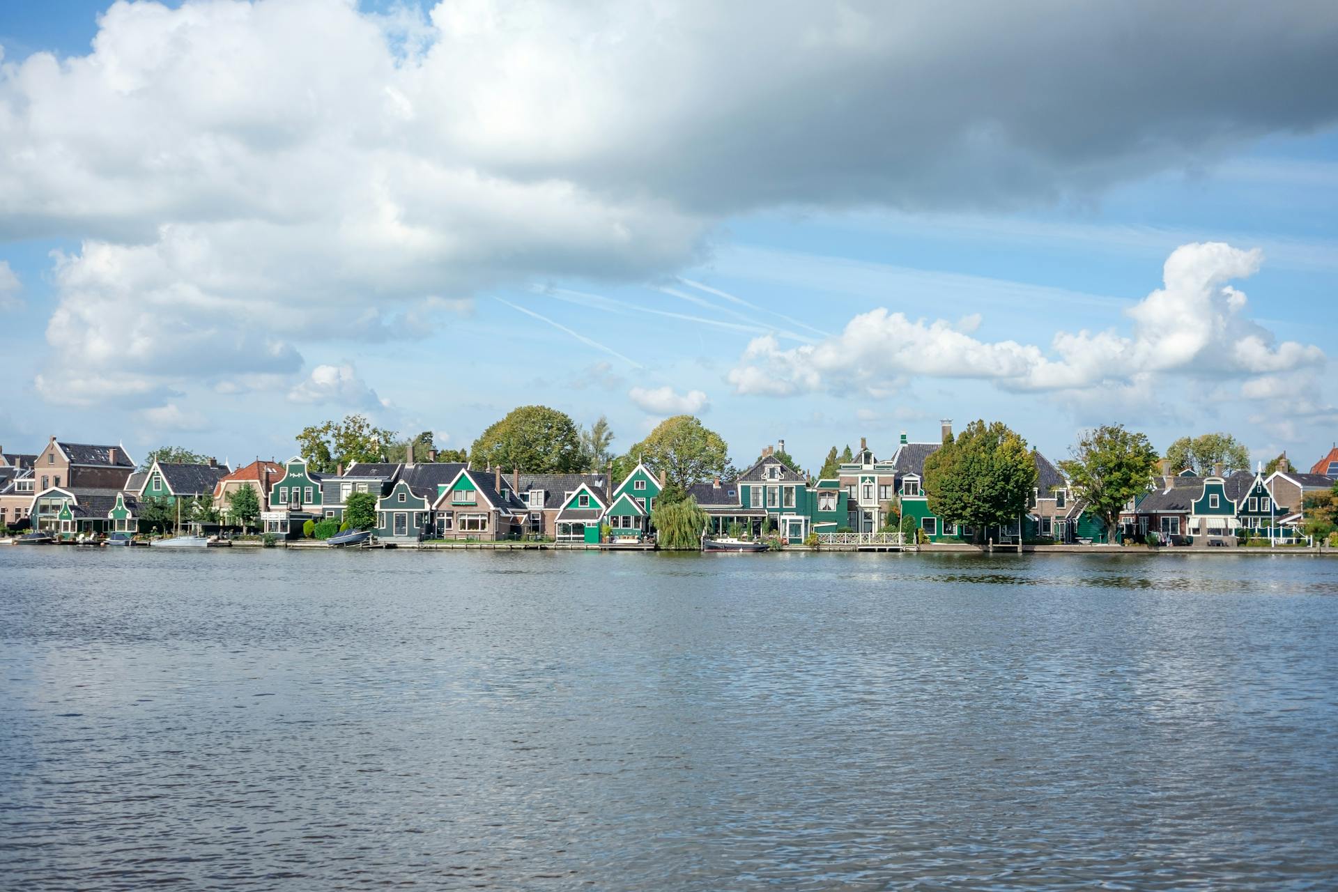 Picturesque view of traditional Zaandam houses by the river under a blue sky.