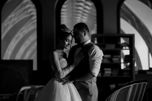Elegant black and white portrait of a bride and groom embracing indoors.