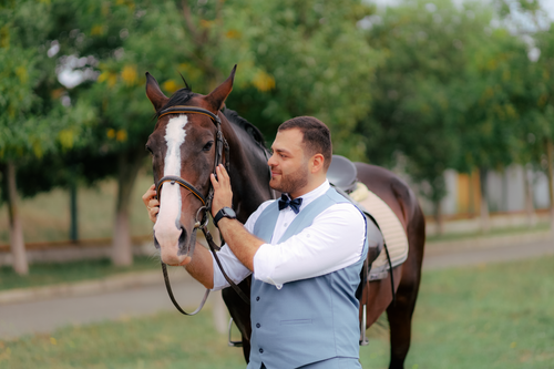 Free A man in formal attire lovingly interacts with a horse outdoors. Stock Photo