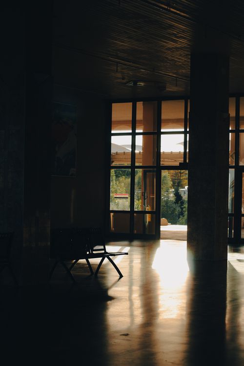 Free A serene indoor scene with sunlight streaming through large windows, casting shadows on the floor. Stock Photo