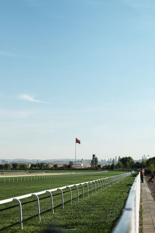 Free Peaceful landscape of a rural horse racing track with a flag and clear blue sky. Stock Photo