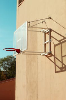 A vintage basketball hoop with a weathered wall under bright sunlight.