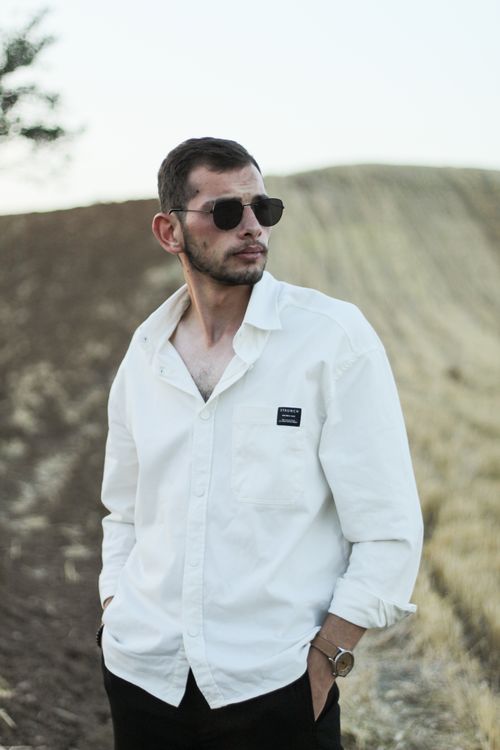 Free Confident man in sunglasses and white shirt in a field under sunny skies. Stock Photo
