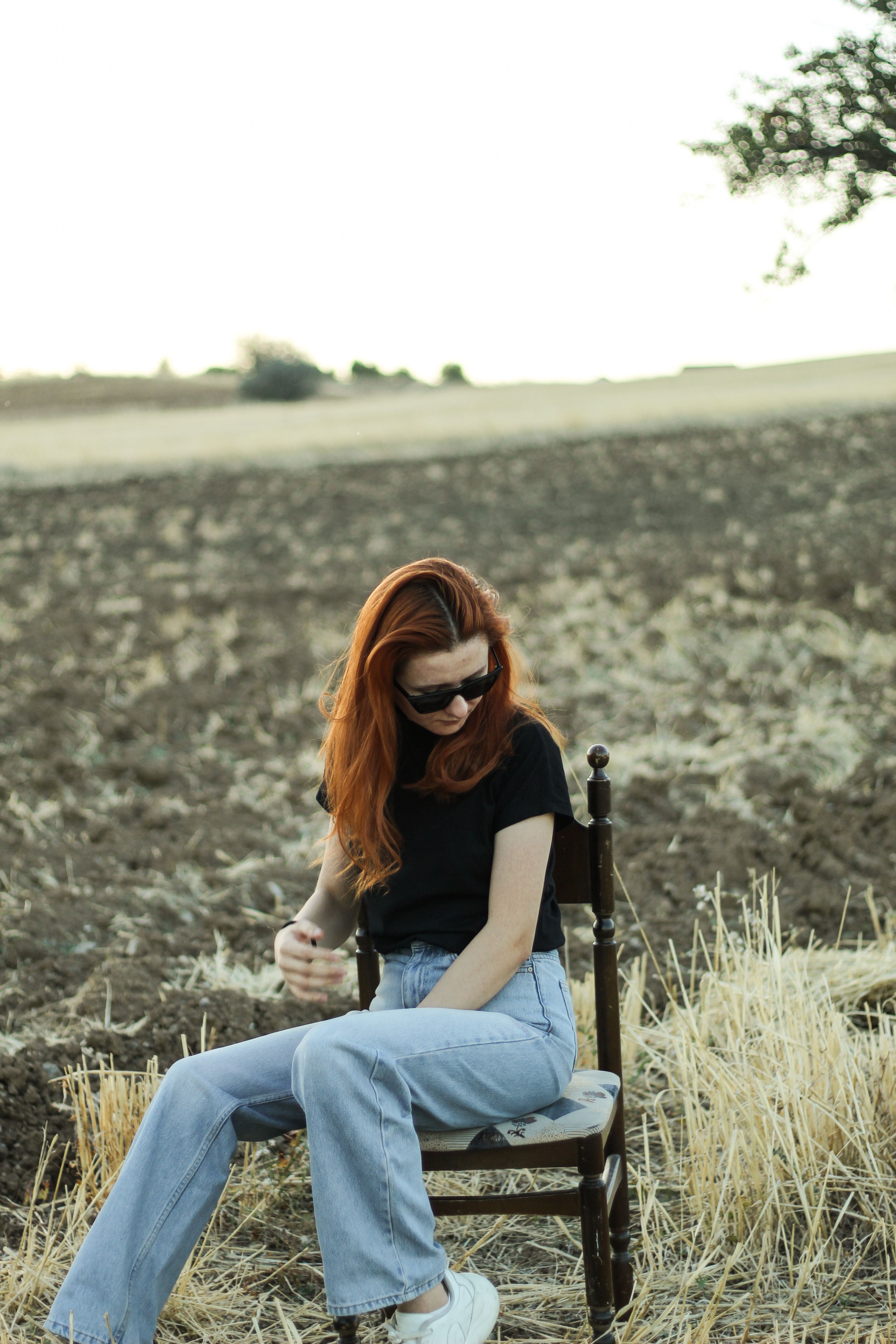 Woman in Black T-Shirt and Jeans Sitting on Wooden Chair · Free Stock Photo