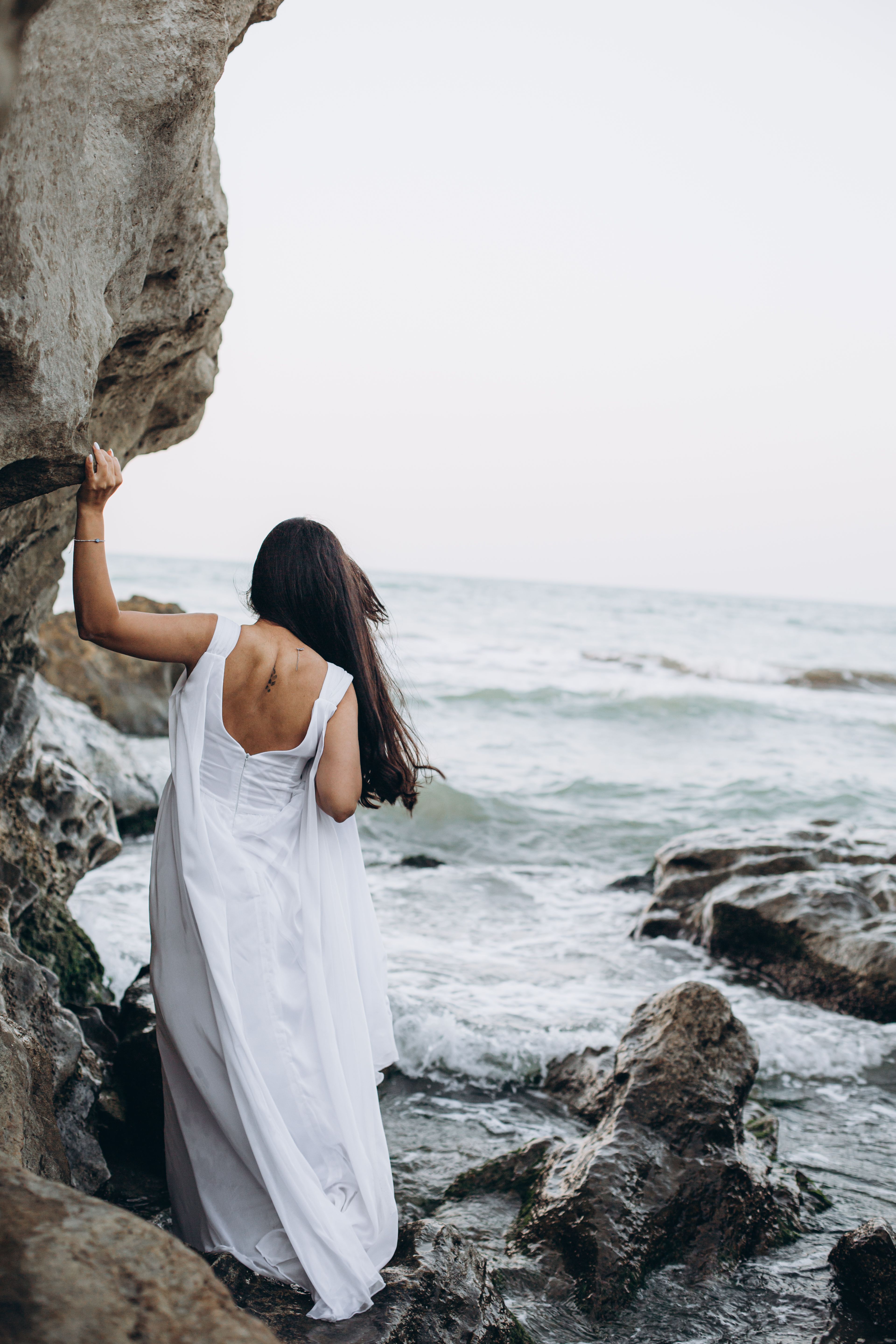 Brunette Woman in White Dress Posing on Rocky Beach · Free Stock Photo
