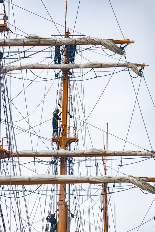 Free Sailors climbing the masts of a grand sailing ship, focusing on rigging work. Stock Photo