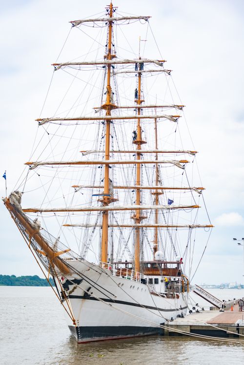 Free A majestic tall ship moored at a harbor, showcasing its impressive sails against a cloudy sky. Stock Photo