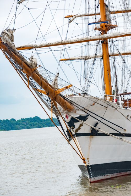 Free A classic sailing ship with intricate masts and sails captured near a lush shoreline. Stock Photo