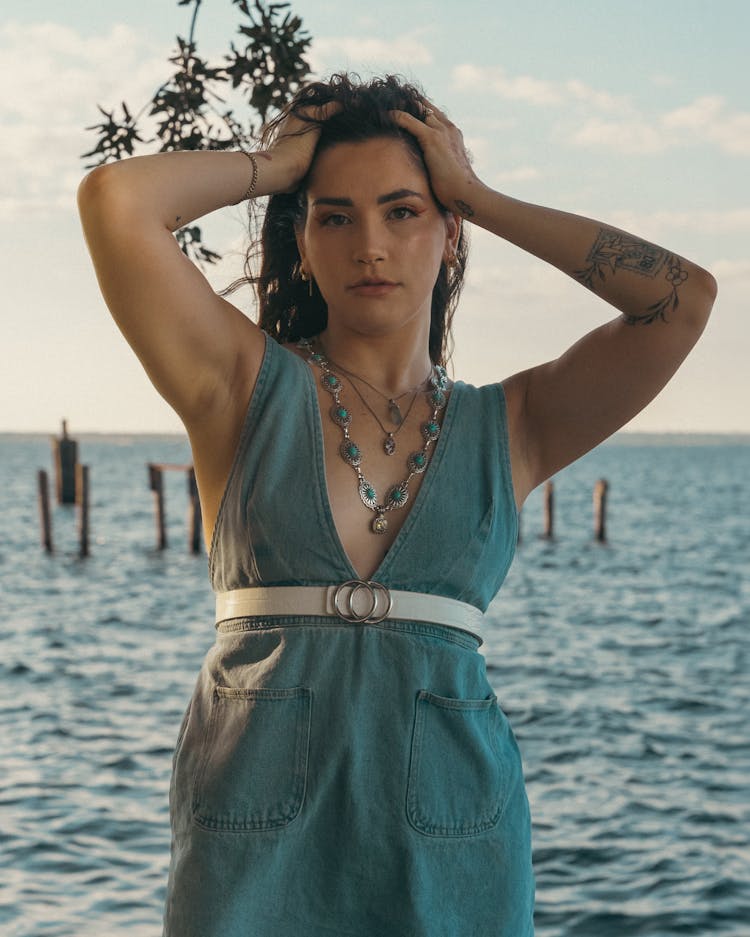 Model Wearing V-Neck Denim Dress And Necklace With Her Hands In Hair