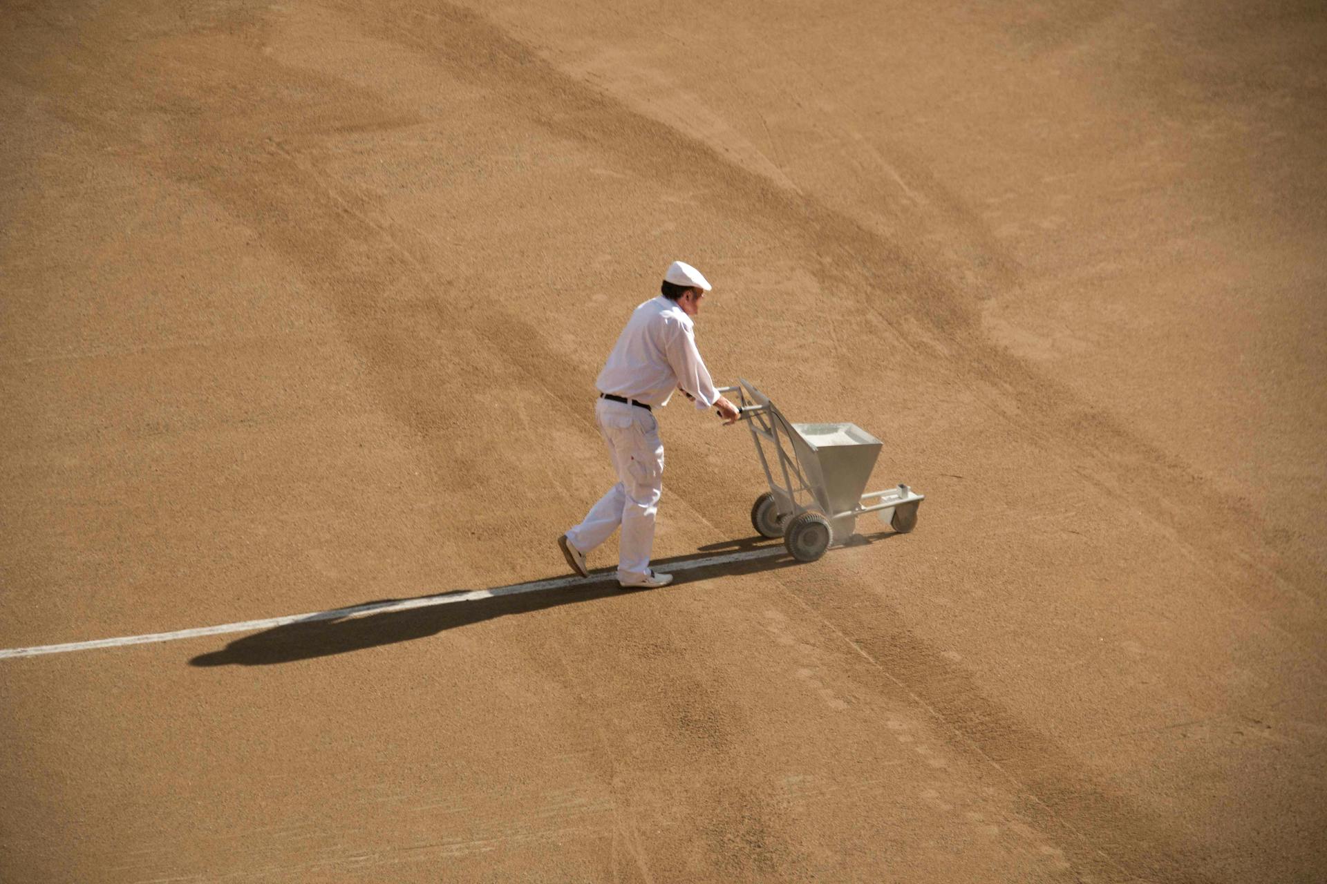 Man with Marker Machine Painting Chalk Line on the Sand