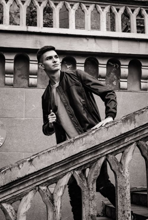 Free Stylish black and white photo of a man in a jacket ascending a staircase in an urban environment. Stock Photo