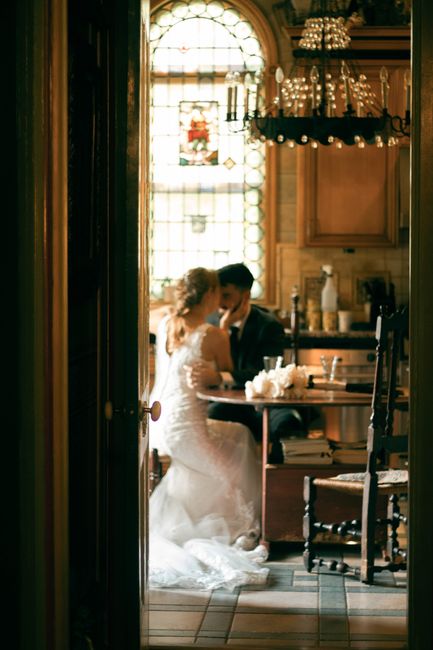 Bride and groom share intimate moment in beautifully lit vintage kitchen.