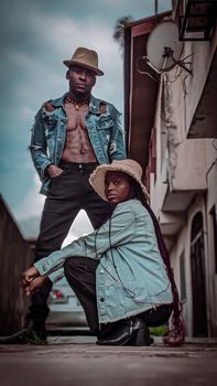 Stylish duo posing in a Lagos alley in denim jackets and hats, showcasing urban fashion.