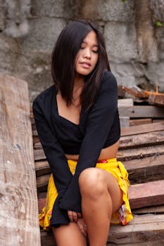 Chic young woman in a fashionable outfit posing outdoors against a textured background.