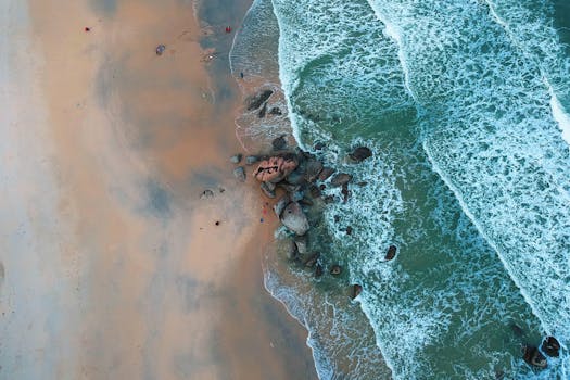A stunning aerial view of Kijal Beach in Malaysia showcasing turquoise waves and rocky shoreline.