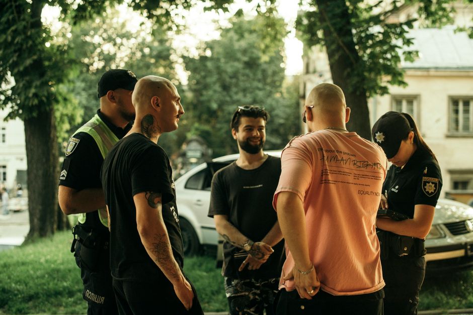A group of people casually interacting with police officers in a park setting in Lviv, Ukraine.