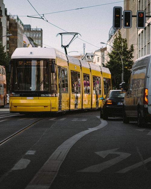 Free Yellow tram navigating through a busy Berlin street with cars and urban buildings. Stock Photo