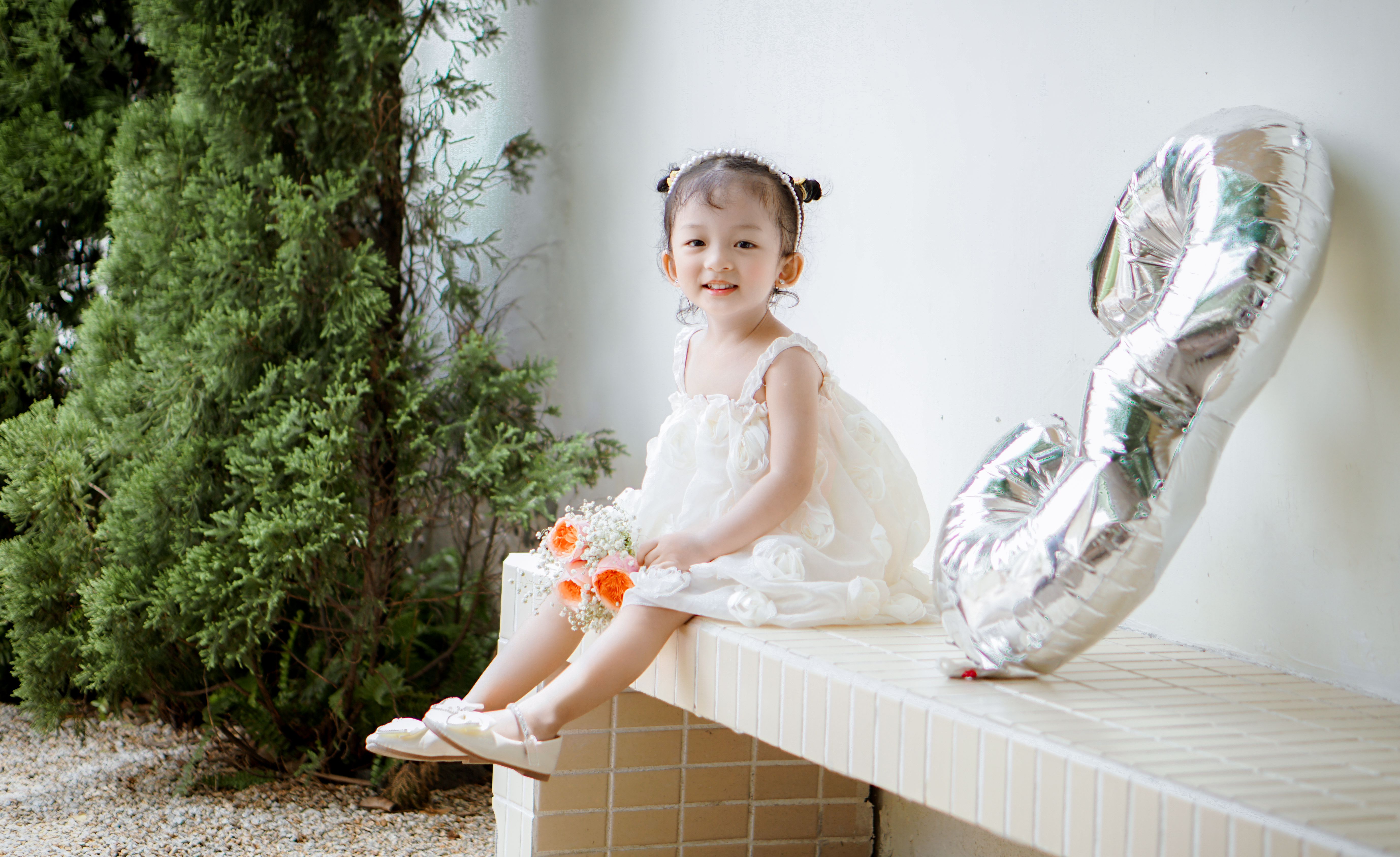 Girl in White Dress Sitting with Birthday Balloon on Bench · Free Stock
