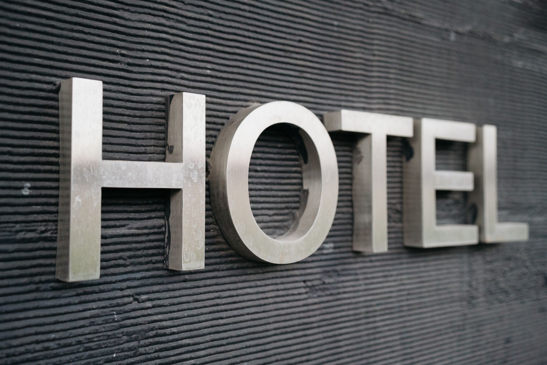 Close-up of a metallic hotel sign mounted on a textured wall. Cover image for HotelNext podcast episode 5.