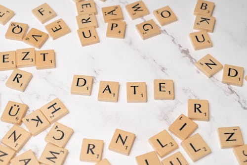 Scrabble letters spelling out the word date on a white marble surface