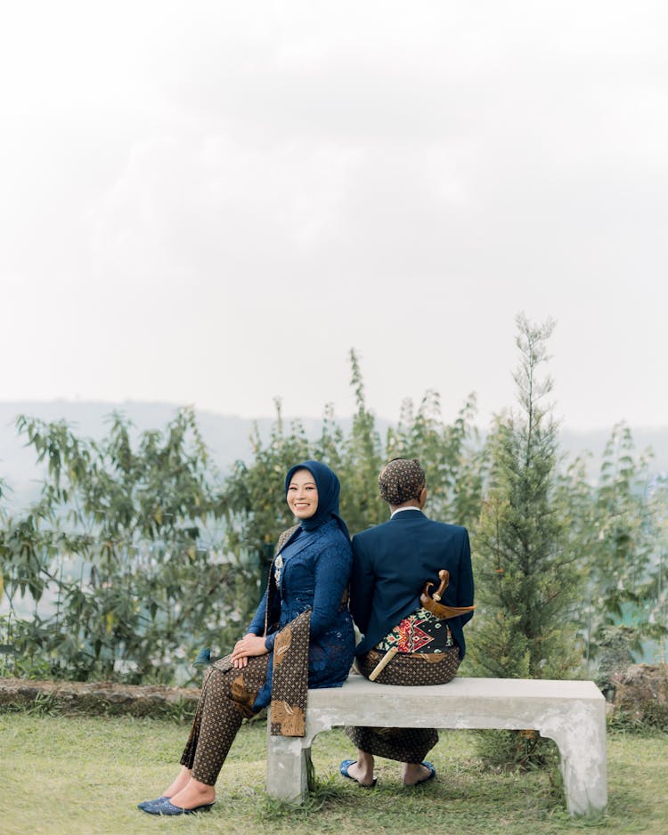 Man And Woman In Traditional Clothing Sitting On A Bench