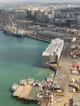 Aerial view of a bustling sea port with cargo ships and containers, highlighting global trade logistics.