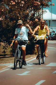 Two women biking in a sunny park in Tortoreto, Abruzzo, Italy, showcasing leisure and outdoor fun.