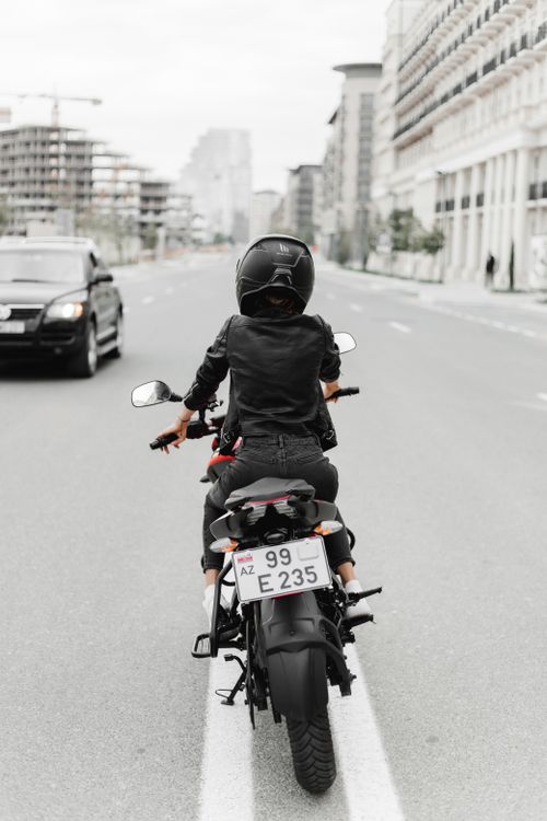 Free A woman in a helmet rides a motorcycle down a city street in Baku, Azerbaijan. Stock Photo