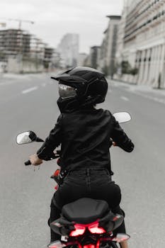 Back view of a woman motorcyclist riding through an empty city street in Baku, Azerbaijan.