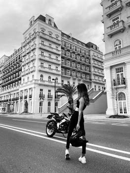Black and white photo of a woman with a motorcycle on the streets of Baku.