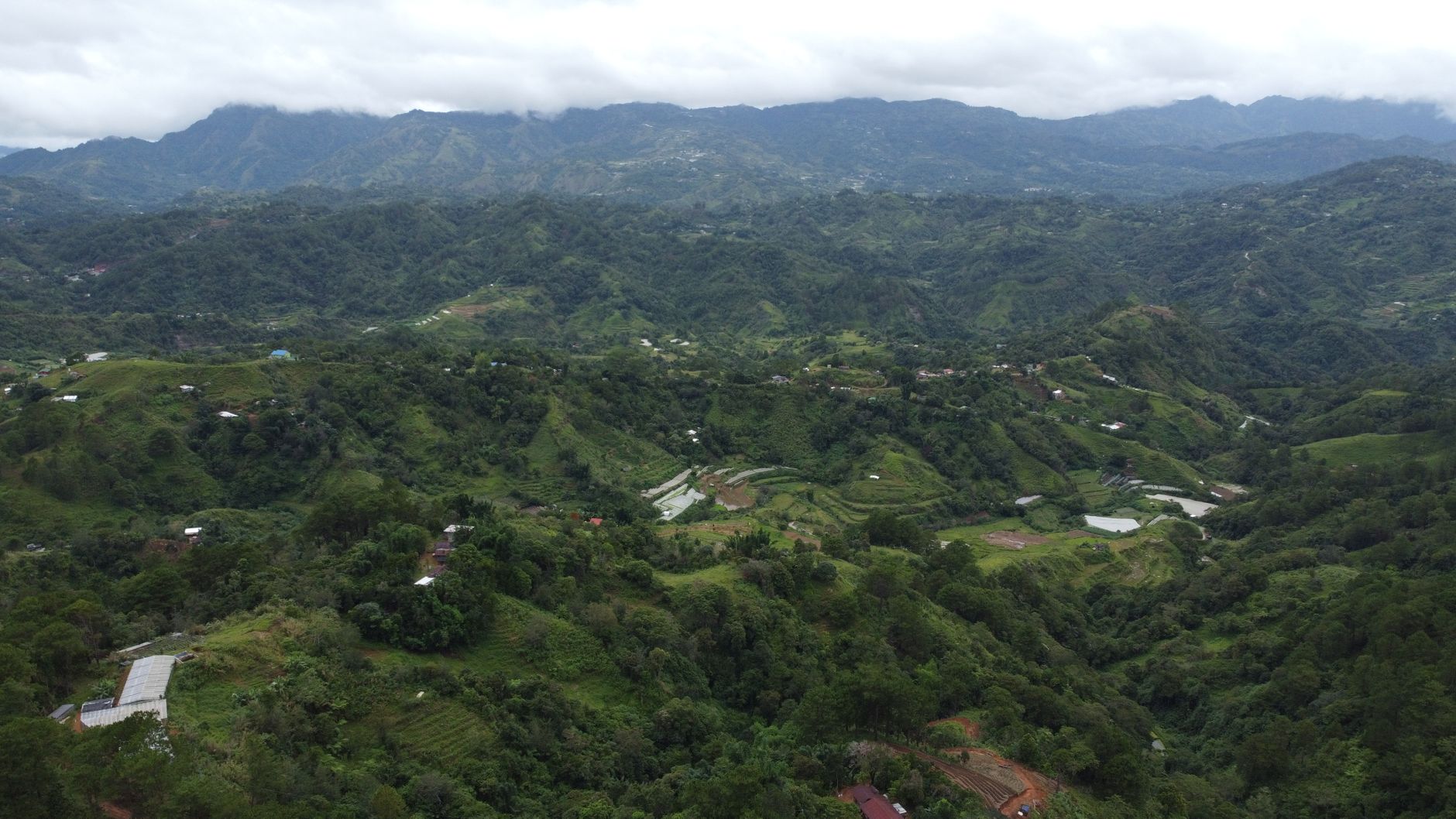 Breathtaking aerial view of Atok's verdant hills under cloudy skies, showcasing lush nature in the Philippines.