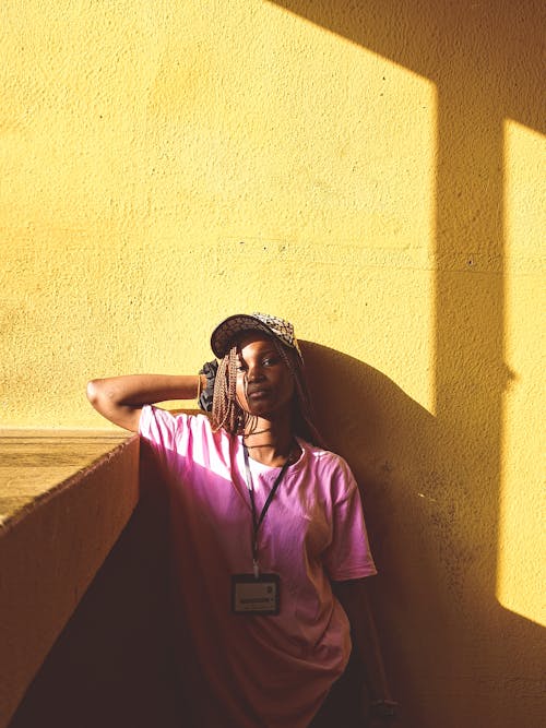 Young Woman in a Casual Outfit Standing beside the Wall in Sunlight