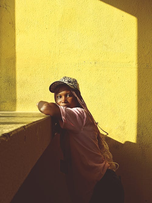 Young Woman in a Casual Outfit Standing beside the Wall in Sunlight