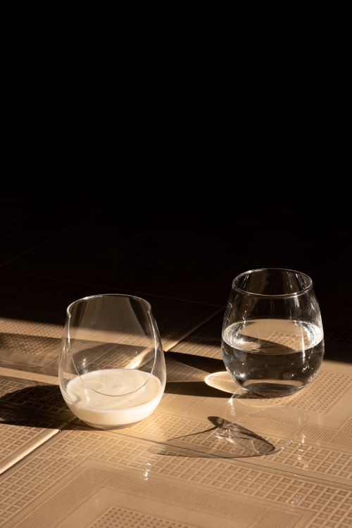 Free Minimalist still life featuring a glass of water and a glass of milk on a lit table. Stock Photo