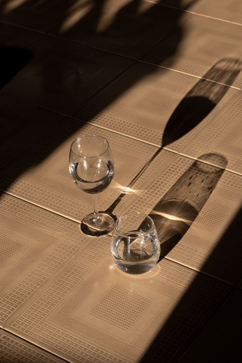 Free A play of light and shadow on a table with glassware creating an elegant still life composition. Stock Photo