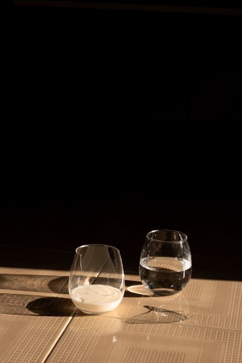 Free Two glasses on a table, one with water and one with milk, in dramatic light. Stock Photo