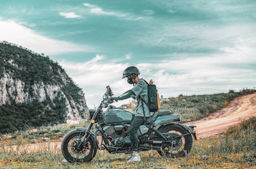 Man on Motorcycle on Side of Dirt Road in Mountains