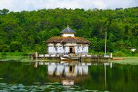 Discover the tranquil Kere Basadi temple surrounded by lush greenery on Varanga Lake in Udupi, India.