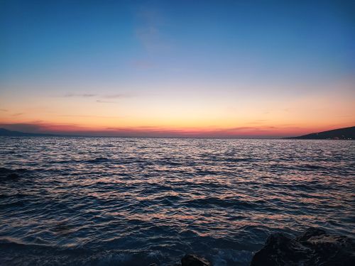 Free Captivating sunset over the ocean with a stunning blend of colorful skies reflected in the waves. Stock Photo