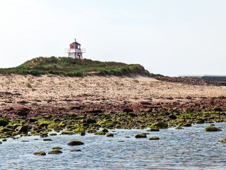 Scenic view of a lighthouse on a sandy coast in Charlottetown, PE, Canada.