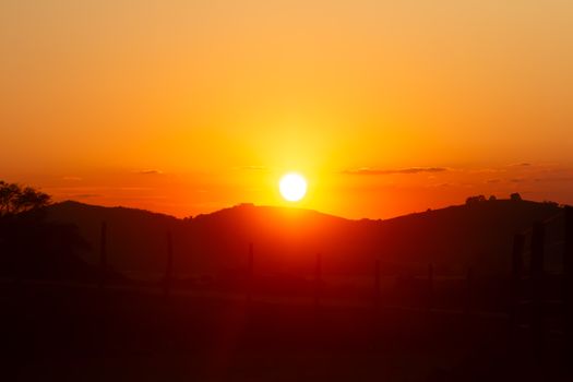 Silhouette of hills at sunset with a vibrant orange sky, perfect for serene landscapes.