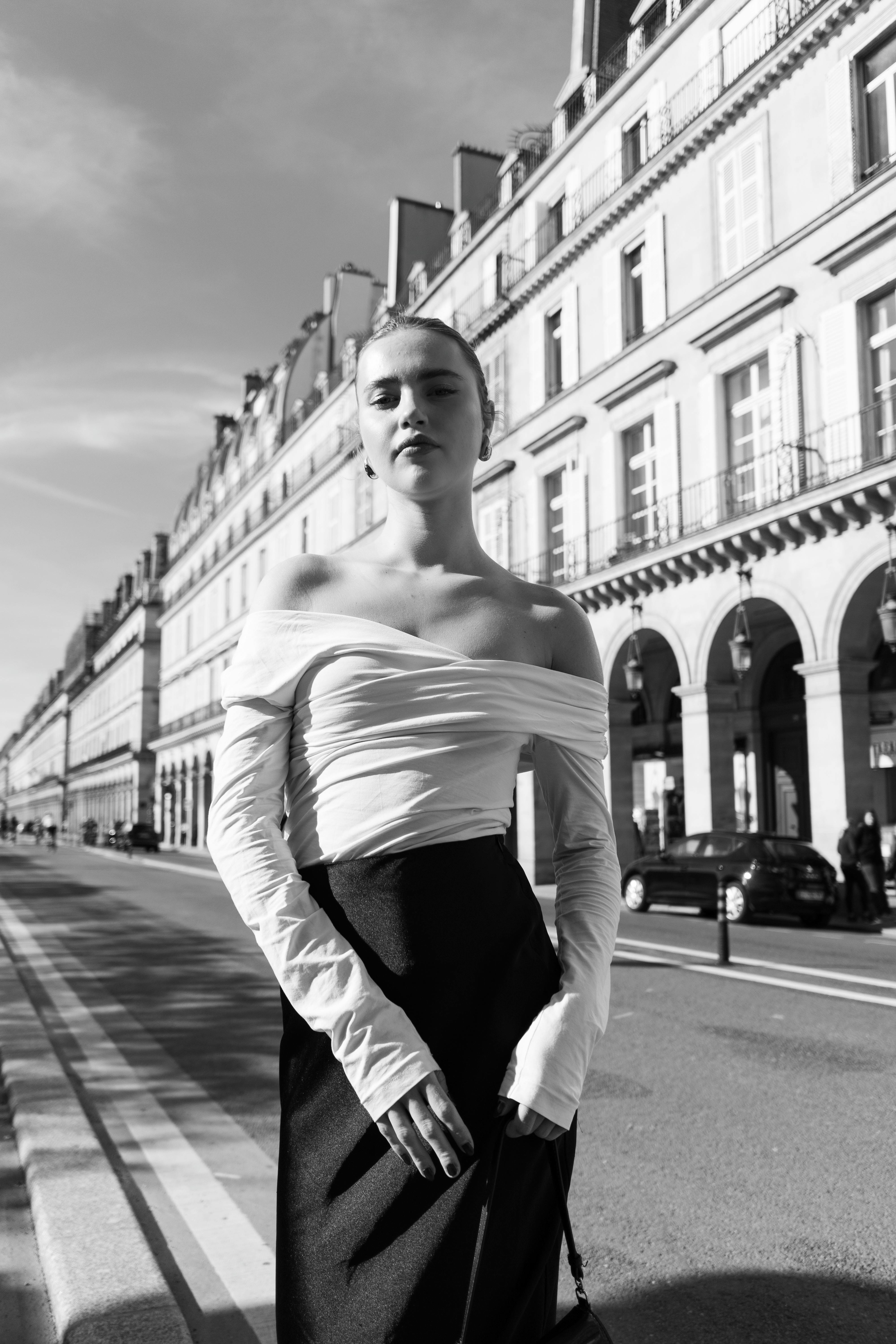 Elegant woman posing on a classic European city street in black and white.