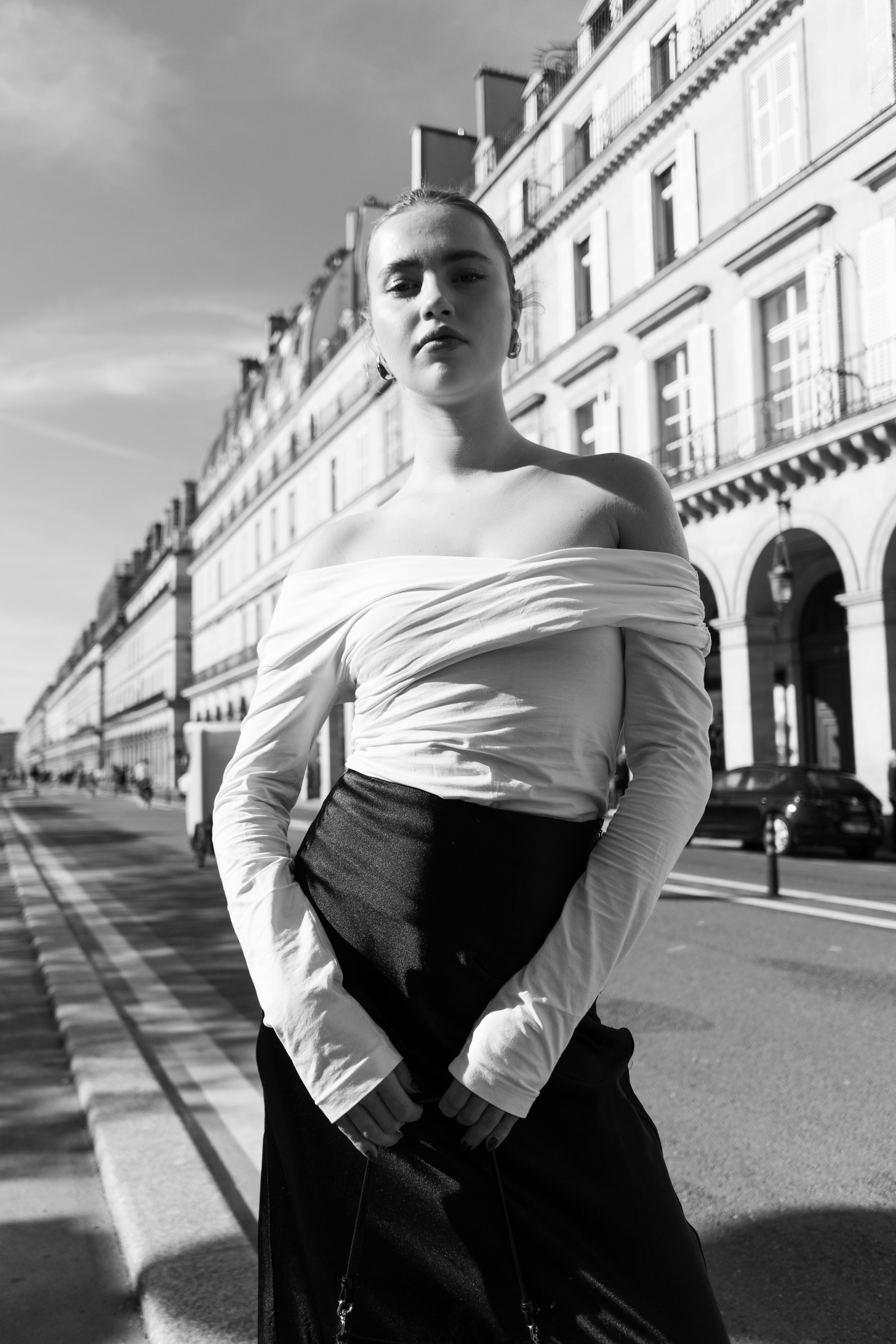 Black and white photo of a woman posing fashionably on an urban city street.