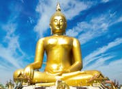 在充满活力的蓝天下，宏伟的金色佛像安静地坐着，象征着宁静