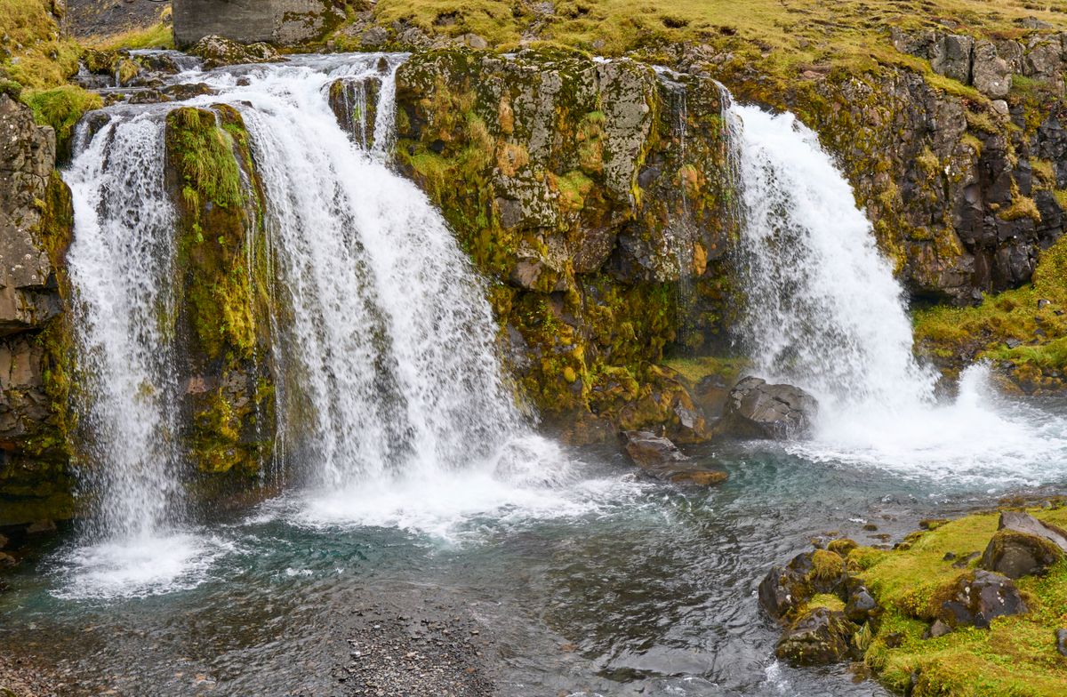 A waterfall in a rocky Icelandic landscape with green moss